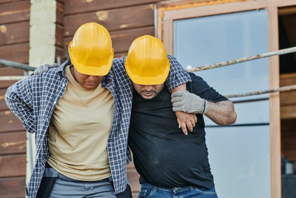 Injured construction worker being helped by coworker