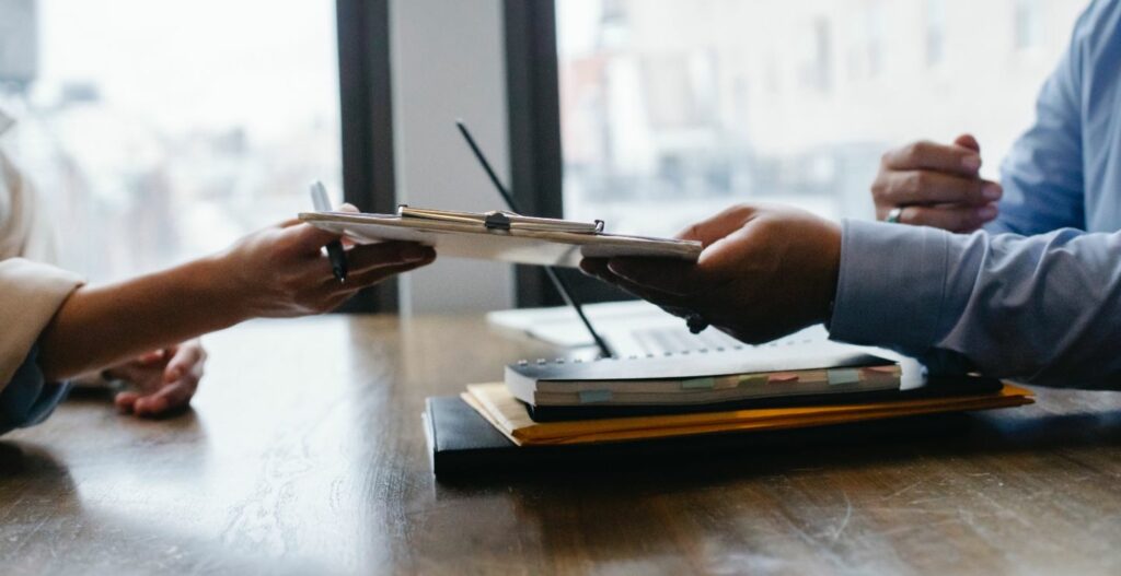 Person handing over a document and pen to sign